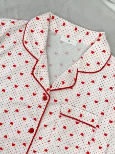 Close-up of white pajama top with red heart and polka dot print and lapel detail.