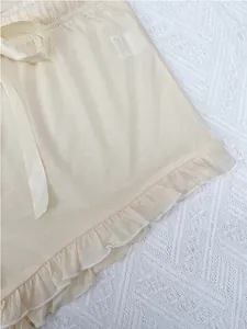 Zoom sur un short de pyjama beige pour femme avec ourlet volanté et nœud satiné.