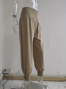 Close-up of beige harem pants with smocked waist and cuffs on a mannequin