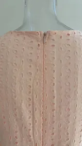 Dettaglio di un abito in pizzo ricamato rosa con cerniera invisibile sul retro della schiena.