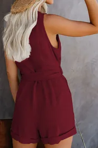 Back view of a maroon sleeveless romper jumpsuit with a waist belt and textured fabric
