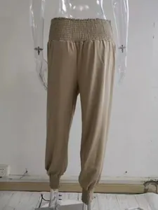Detailed back view of women's khaki smocked waist harem pants on clear mannequin.