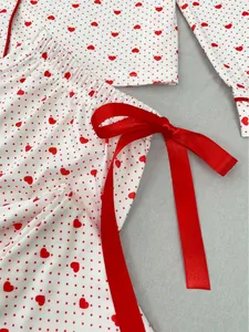 Close-up of red ribbon bow and heart print detail on white pajama pants