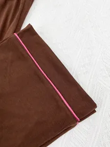 Détail en gros plan d'un pyjama en maille marron avec un passepoil rose vif décoratif