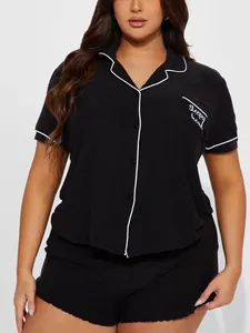 Vue détaillée du haut de pyjama noir pour femme avec liseré blanc et broderie