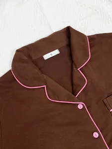 Détail d'un haut de pyjama marron avec passepoil rose vif et petite étiquette de taille