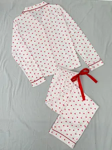 Detail view of a white women's pajama set with red heart prints and a ribbon bow.