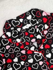 Close-up detail of women's pajama collar featuring heart print and red contrast trim piping