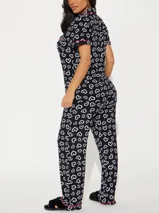 Detailed side view of women's black heart print pajama set featuring red piping accents