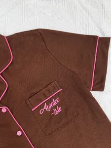 Détail du haut de pyjama marron avec broderie rose sur la poche de poitrine