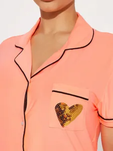 Close-up of peach short-sleeved pajama top with a sequin heart on the chest pocket.