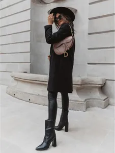 Street style fashion shot of a black mid-length wool coat paired with chic high-heeled boots