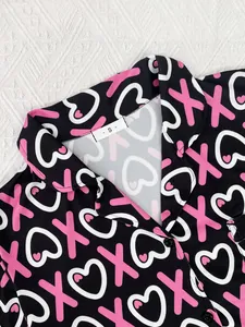 Detail shot of women's black pajama top featuring pink heart print and size S label