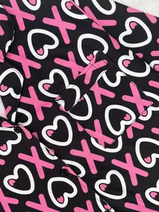 Close-up detail of women's pajamas featuring pink X and heart pattern with a pocket.