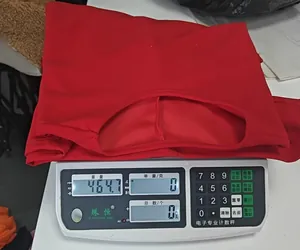 Detailed view of an elegant red round neck dress being weighed on a digital scale