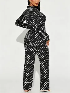 Rear view of women's black and white polka dot pajama set with white piping detail.