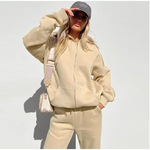 Side view of woman wearing a beige oversized fleece hoodie and matching jogger pants set