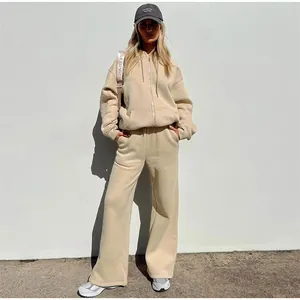Full-length street style detail of a beige oversized hoodie and sweatpants tracksuit.