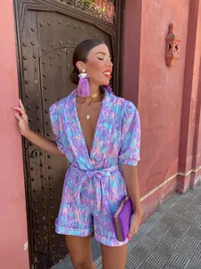 Close-up of vibrant purple printed deep V-neck jumpsuit with puff sleeves and belt
