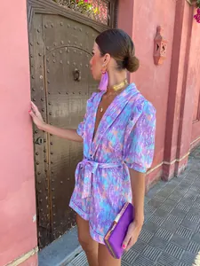 Detailed view of a vibrant purple printed deep V-neck romper with puff sleeves
