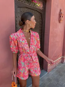 Close-up of vibrant pink printed romper with deep V-neck, puff sleeves and belted waist