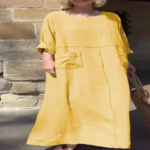 Close-up detail of a yellow linen maxi dress featuring a round neck and double front pockets.