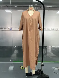 Detail of a brown V-neck maxi dress with pleated chest and side slits on mannequin