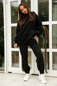 Une femme porte un sweat à capuche noir oversize élégant avec un pantalon de jogging assorti.