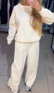 Détail d'un ensemble sweat et pantalon de jogging blanc orné de strass sur un mannequin.