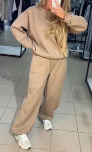 Selfie miroir d'un mannequin portant un ensemble de jogging beige orné de strass.