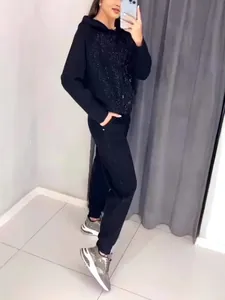 Detailed view of women's black tracksuit with sparkling sequin embellishments
