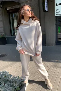 Mannequin caucasien posant dans un ensemble deux pièces beige avec sweat à capuche et jogging.