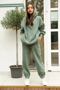 Détail d'un ensemble deux pièces sweat à capuche et jogging vert sauge sur modèle.