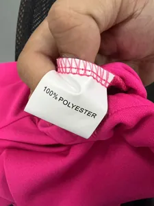 Close-up of pink fabric garment label showing 100% polyester material composition