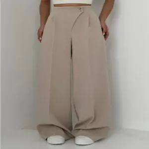 Detailansicht der beigen Hose mit hohem Bund, weitem Bein und versetztem Knopfdesign