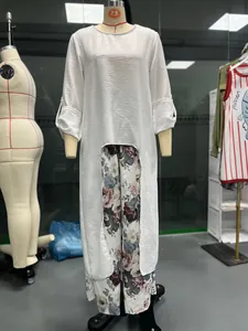 Detailansicht eines Damen-Zweiteilers mit weißer unregelmäßiger Tunika und floraler weiter Hose