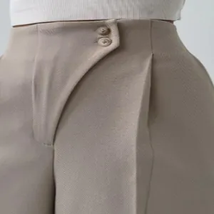Detailansicht einer beige Hose mit hoher Taille und asymmetrischem Knopfverschluss