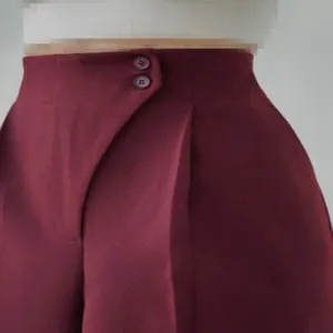 Detailansicht der weinroten High-Waist-Hose mit doppeltem Knopfverschluss am Bund
