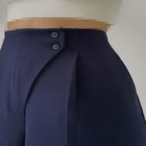Nahaufnahme einer dunkelblauen schmalen Hose mit elegantem Knopfdetail am Bund