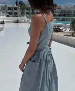 Back view of a light blue sleeveless sundress with side pockets in a resort setting