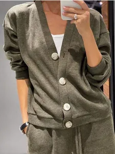 Detalle de cárdigan de punto verde oliva con botones blancos y pantalón a juego
