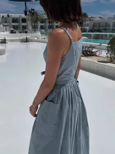 Elegant light blue sleeveless midi sun dress with pockets shown in a resort setting