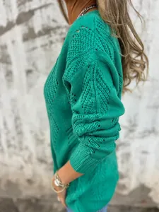 Detail view of emerald green V-neck knit sweater with intricate hollow leaf pattern