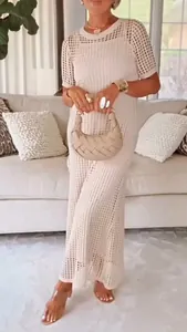 Detailed shot of a chic beige crochet maxi dress with elegant hollow-out knit pattern.