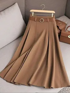 Détail d'une jupe midi plissée marron avec ceinture assortie et boucle dorée sur un cintre