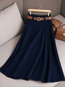 Vue détaillée de haute qualité d'une jupe plissée bleu marine avec ceinture marron sur canapé