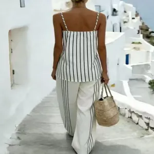 Back view of woman wearing navy striped camisole top and wide-leg trousers in summer resort.