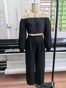 Detailed view of black off-the-shoulder crop top and trousers set on mannequin.