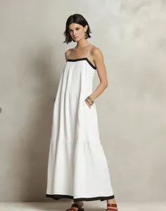 Elegant white tiered maxi dress featuring black contrast trim and thin spaghetti straps.