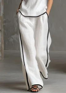 Dettaglio del top bianco senza maniche e dei pantaloni larghi con profili neri